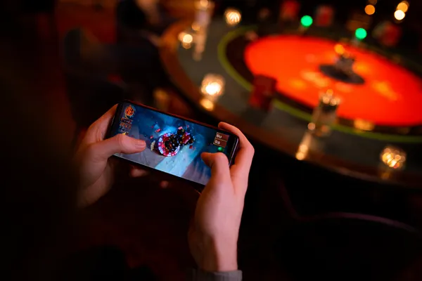 Um jogador usando seu smartphone durante um evento festivo local, representando o cassino totalmente compatível com dispositivos móveis do 777AN.